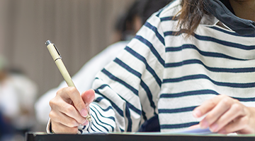 Photo d'une étudiante tenant un stylo lors d'un examen