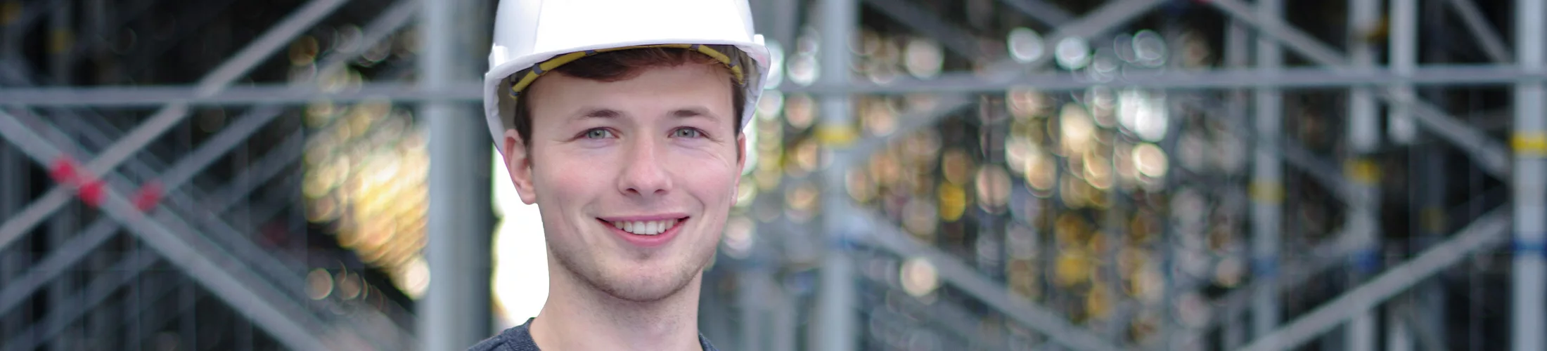 Photo d'un étudiant souriant avec un casque de chantier