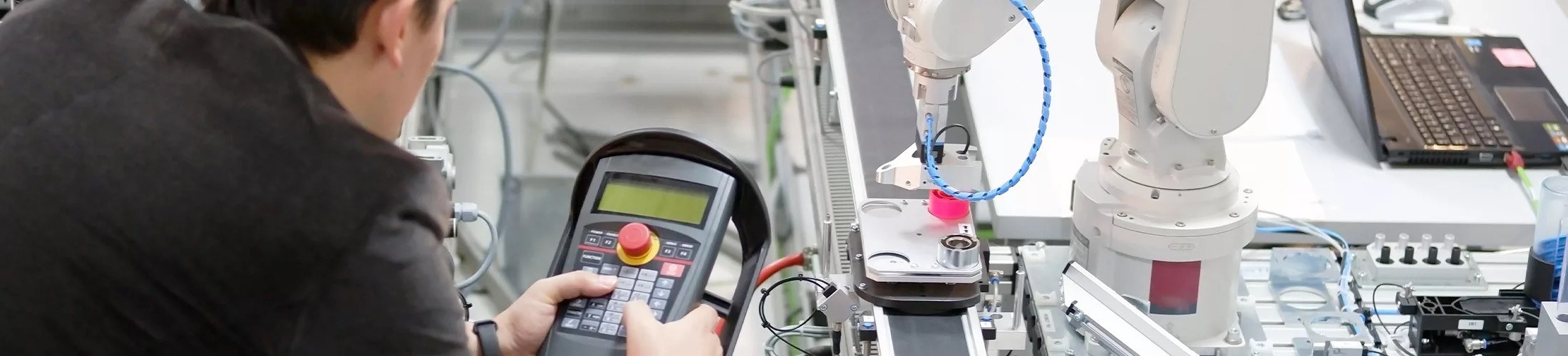 Photo d'un professeur commandant avec une télécommande un robot sur une chaine de montage