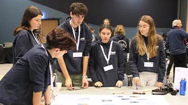 Photo d'un groupe d'étudiant avec des sweats noirs en séance de travail collaboratif