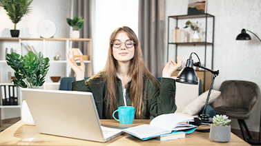 Photo d'une fille derrière son bureau en position de méditation