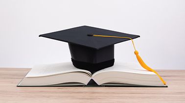 Photo d'un livre ouvert avec un chapeau d'universitaire
