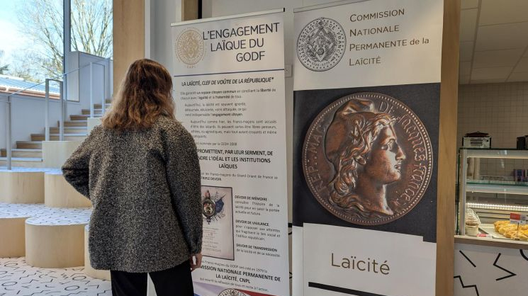 Photo d'une personne devant les panneaux de l'expo Laïcité.